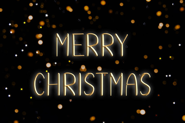 Words MERRY CHRISTMAS on a black background. - Фото, изображение