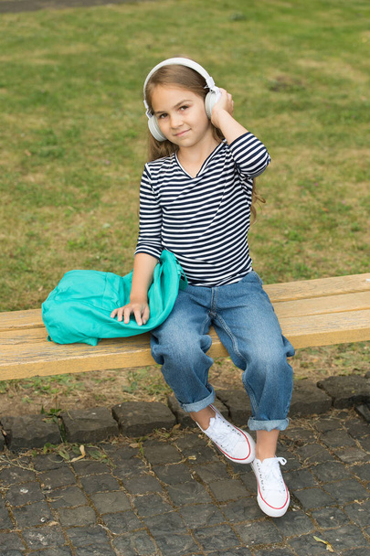 School out, summer in. Little kid listen to music in headphones outdoors. Summer vacation. School holidays. Musical education. Fun and entertainment - Fotó, kép