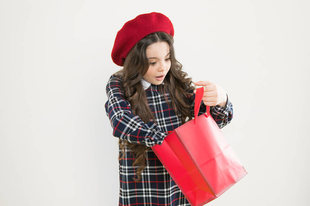 Just a minute of surprise. Little girl looking for surprise gift on yellow background. Small child holding shopping bag with surprise. Adorable shopper with surprise emotion on face - Foto, Bild