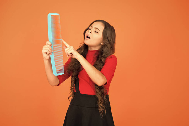 Give your hair a comb. Small child touch comb tooth brown background. Plastic hair comb. Combing tool. Beauty salon. Hairdressing. Hairstyling. Haircare routine. Best detangling comb - Fotografie, Obrázek