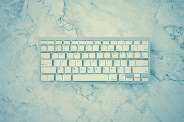 Modern Clean White Computer Keyboard on Flat Lay or Top View Office Desk or Office Table on Marble Minimalist Background in Vintage Tone - Photo, Image