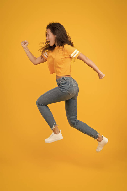 Run hard to arrive at goal. Dynamic woman run yellow background. Sexy girl jump with long run. Energetic look of fashion model. Casual style. Active lifestyle. Run and become - Φωτογραφία, εικόνα