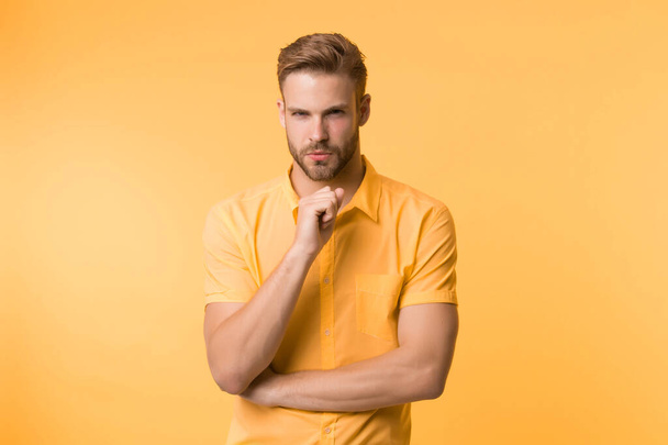 Asking himself. Handsome young man keeping hand on chin while stand yellow background. Existentialism concept. Hard question. Moral question difficulties. Listen to yourself. Question without answer - Photo, image