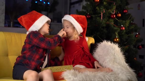 freche kleine Bruder und Schwester in Weihnachtsmützen lächeln und umarmen - Filmmaterial, Video