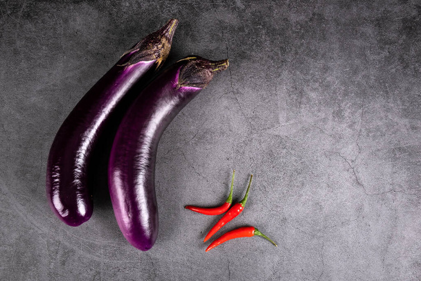 Chinese Eggplants and Hot Red Chili Peppers on Grey Textured Background - Фото, зображення