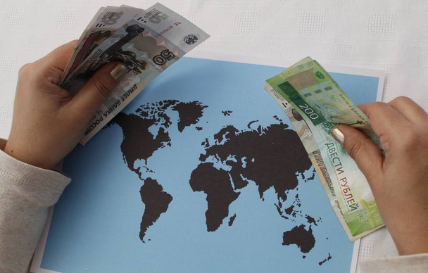 Руки жінки, яка тримає російські гроші і мапу світу. - Фото, зображення