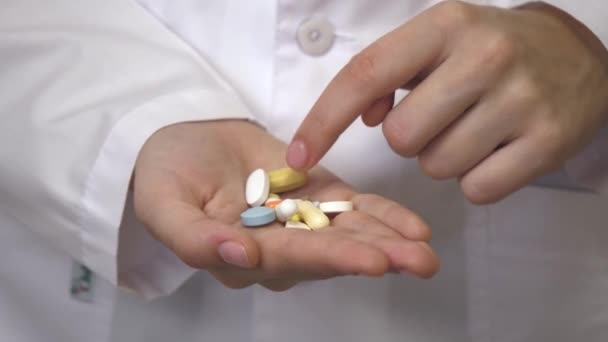 Pilules analgésiques dans la main féminine d'un professionnel de la santé dans un manteau blanc. Capsules avec médicaments, prise de médicaments, soins de santé, pharmacie et concept de traitement, vue rapprochée - Séquence, vidéo