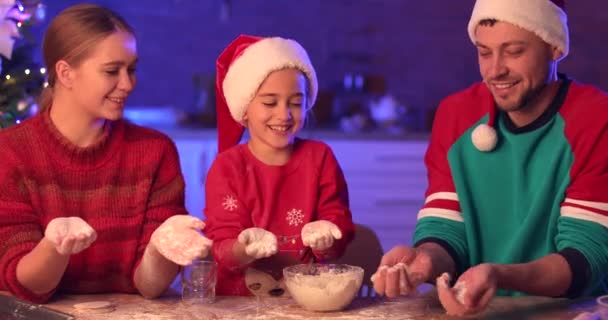 Familia feliz divirtiéndose mientras hace galletas de jengibre para Navidad en la cocina - Metraje, vídeo