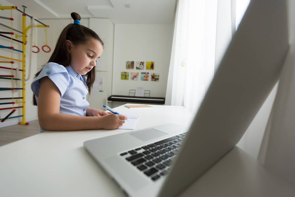 Melko tyylikäs koulutyttö opiskelee kotitehtäviä matematiikan aikana hänen online-oppitunti kotona, sosiaalinen etäisyys karanteenin aikana, itsensä eristäminen, online-koulutuksen käsite, kotiopettaja - Valokuva, kuva