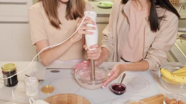 Images d'en haut de la section médiane de maman et fille cuisinent ensemble en mélangeant des ingrédients pour une crème glacée maison saine à l'aide d'un mélangeur d'immersion - Séquence, vidéo
