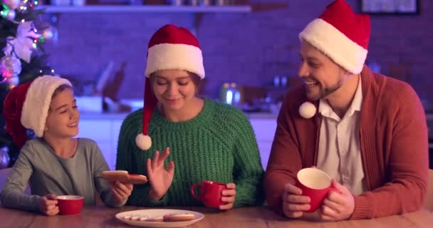 Boldog család eszik ízletes mézeskalács cookie-k a konyhában karácsony este - Felvétel, videó