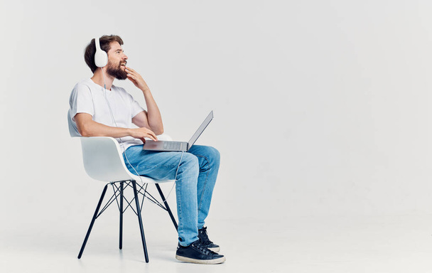 Kulaklıklı bir adam dizüstü bilgisayarının önünde oturmuş iletişim teknolojisi ofisinde oturuyor. - Fotoğraf, Görsel