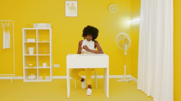 女性は創造的な黄色の部屋で軽食を持っています - 映像、動画