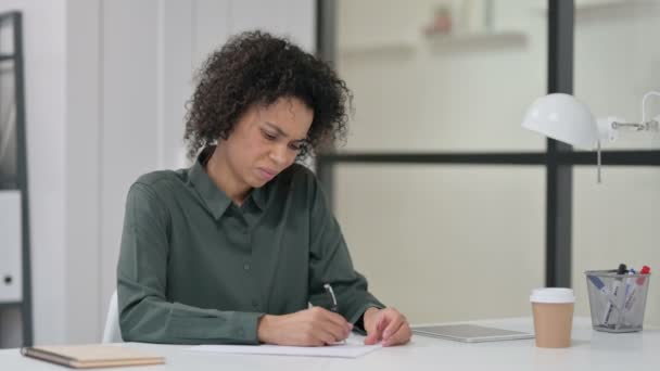 Mujer africana incapaz de escribir sobre papel en el trabajo  - Imágenes, Vídeo