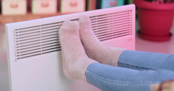 Mladá žena oteplování nohy v blízkosti elektrického ohřívače doma - Záběry, video