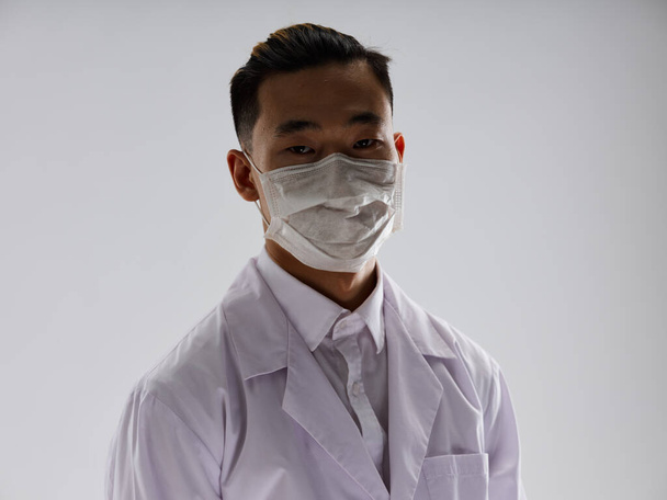 Mies lääkäri maski valkoinen takki terveys harmaa tausta - Valokuva, kuva