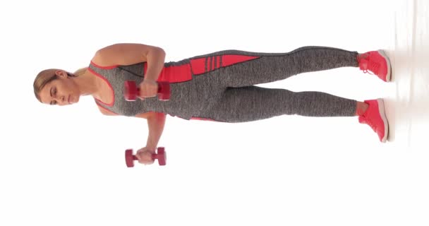 Mujer joven deportiva entrenando con pesas sobre fondo blanco - Metraje, vídeo
