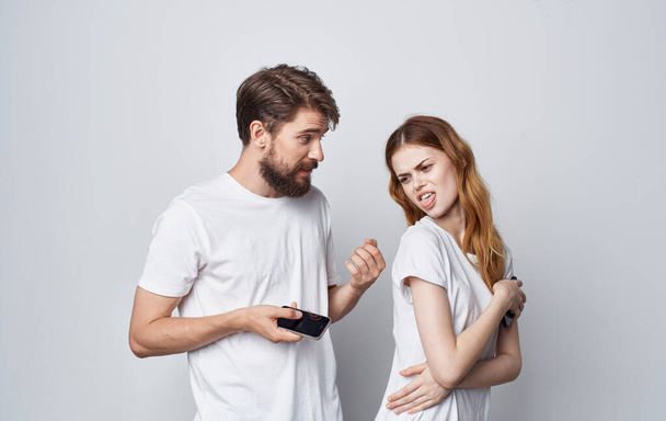 mies ja nainen valkoisissa t-paidoissa puhelimilla käsissä romantiikkaa viestintätekniikka - Valokuva, kuva
