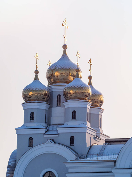 The golden domes of the Christian church are covered with snow in winter. Orthodox temple with golden domes. - Foto, imagen