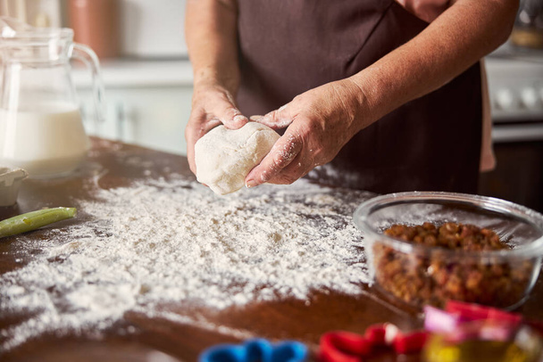 Experienced baker with a bulky piece of dough in hands - Photo, Image