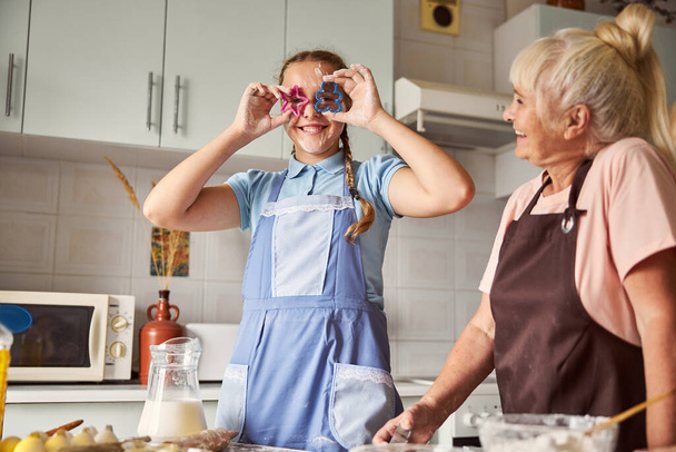 Feliz abuela y encantadora nieta divirtiéndose con la cocina - Foto, imagen