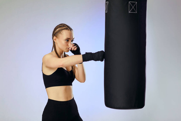 sporty brunette woman with boxing bandageshitting the boxing bag - Foto, Imagem