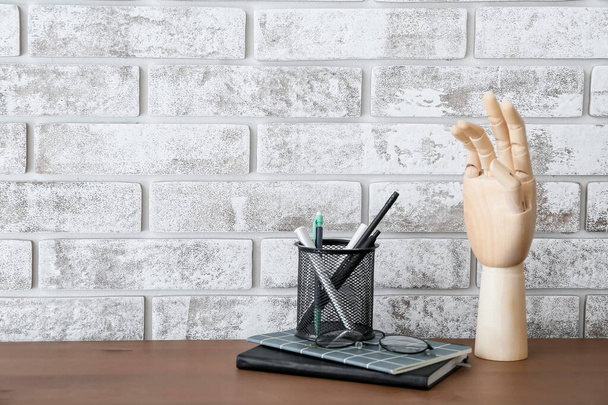 Ξύλινο χέρι με βάση για μολύβια, στυλό και σημειωματάρια στο τραπέζι - Φωτογραφία, εικόνα