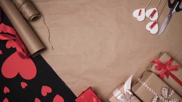 Bovenaanzicht van mannelijke handen verstrooien beeldjes in de vorm van rode harten op de tafel met geschenken. Valentijnsdag concept. - Video