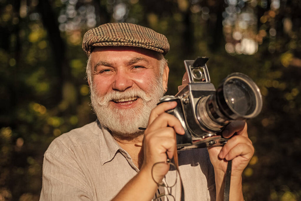 Vintage style. Travel Lifestyle vacations concept. Man photographer holding a vintage camera. Bearded man. Lifestyle and travel concept. Give me a smile. The concept of macro nature photography - Foto, afbeelding