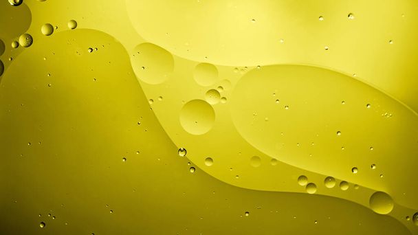 olej s bublinkami na žlutém pozadí. Oranžové abstraktní vesmírné pozadí. Měkké selektivní zaměření. makro ropných kapek na vodní hladinu. kopírovat prostor. vzduchové bubliny ve vodě. barva 2021 - Fotografie, Obrázek