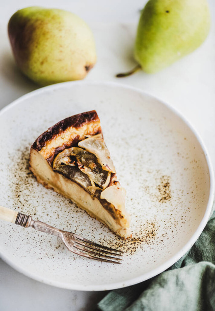 Piece of vegan dairy-free sugar-free pear cheesecake in rustic plate over white marble table background, top view. Modern vegetarian healthy dessert concept - Foto, imagen
