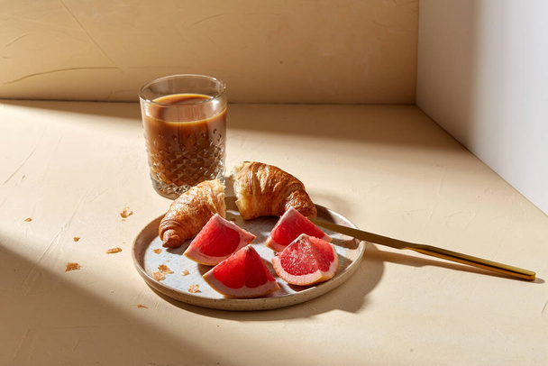 glass of coffee, croissant and grapefruit on table - Foto, Bild