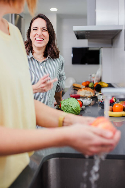 Frauen, die gesunde Nahrung zubereiten und Gemüse in der Küche waschen, Spaß haben, Ernährungskonzept. - Foto, Bild