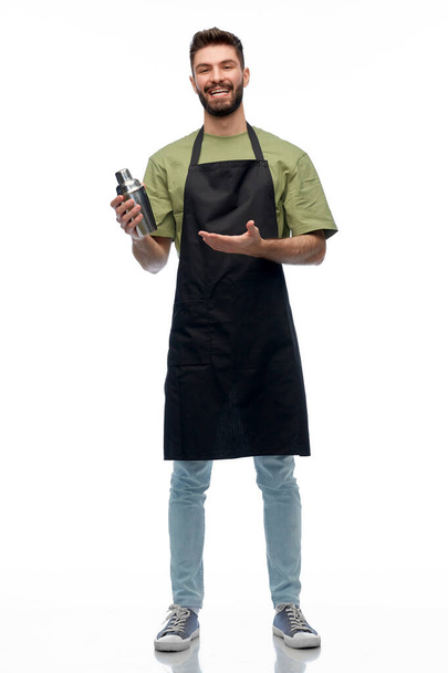 happy barman in apron with shaker - Foto, afbeelding