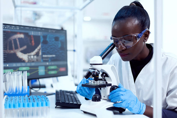 Virologin afrikanischer Herkunft sitzt an ihrem Arbeitsplatz im schmucken Reagenzglas - Foto, Bild