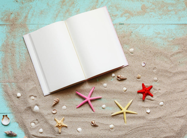 Summer background with notepad and seashells on sand on wooden turquoise background. Holiday planning. Summer time, vacations, travel, tourism. Top view. Place for text. - Photo, Image