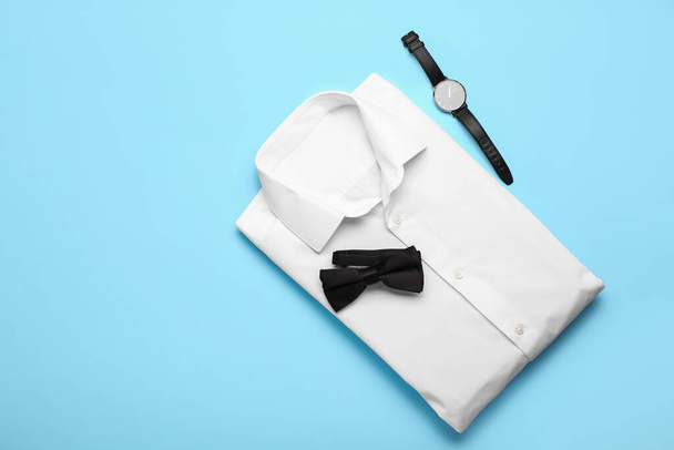 Новая мужская рубашка, наручные часы и галстук-бант на цветном фоне - Фото, изображение