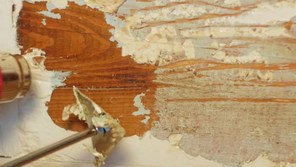 Легкая и дешевая реставрация деревянных дверей. Столяр-реставратор снимает краску с окрашенной поверхности деревянной доски с помощью теплового пистолета высокой температуры и лопатки. Проект домашнего интерьера DIY - Кадры, видео