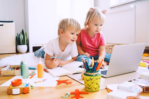 Kids using computer online technology to art creative, drawing or making crafts. Preschool children distance online education. Family leisure with little children at home or daycare. - 写真・画像