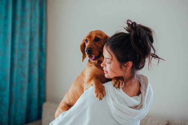 A woman at home holds a dog in her arms - Φωτογραφία, εικόνα