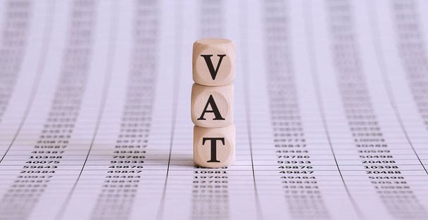 Trzy drewniane kostki z literami VAT, na wykresie, biznes - Zdjęcie, obraz