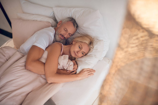 Mature couple sleeping on a bed together - Foto, immagini