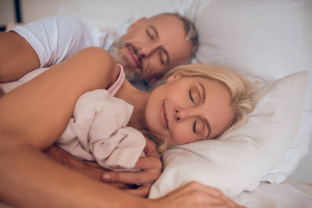 Mature couple sleeping on a bed together - Fotoğraf, Görsel