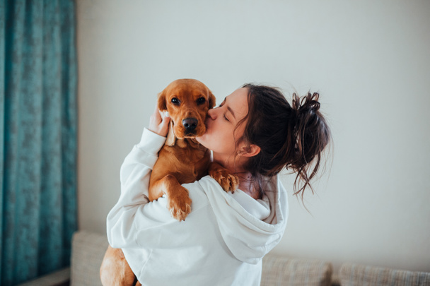 A girl in a white hoodie kisses a dog - Fotoğraf, Görsel