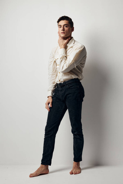 A man in full growth In a bright room and a white shirt, dark trousers model - Photo, Image