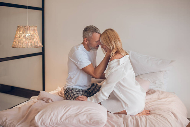 Bearded man hugging a blonde woman and looking romantic - Φωτογραφία, εικόνα