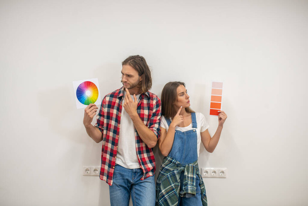 Young couple discussing the color for walls and looking uncertain - Foto, immagini