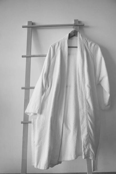 White Clean bathrobe hanging on wooden hanger  - Foto, afbeelding