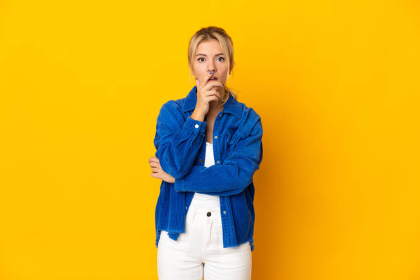 Young Russian woman isolated on yellow background surprised and shocked while looking right - Fotoğraf, Görsel