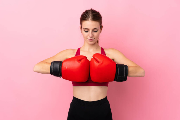 Mujer deportiva joven sobre fondo rosa aislado con guantes de boxeo - Foto, Imagen